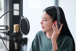 un' donna è registrazione un' canzone nel un' studio foto