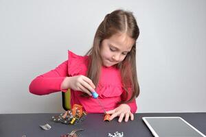 poco ragazza viti metallo parti su un' robot. concetto di mani su apprendimento, formazione scolastica, creatività, e ingegneria esplorazione foto