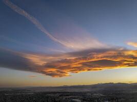 nuvole e scie di condensazione al di sopra di roccioso montagne ai piedi e città di forte collins, Colorado, nel Alba leggero foto