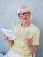 donna anziana con gli occhiali che legge le istruzioni di medicina. età, assistenza sanitaria, concetto di trattamento foto