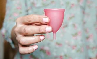 primo piano della mano della donna che tiene la coppetta mestruale foto