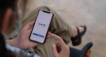 una donna tiene in mano apple iphone xs con l'applicazione linkedin sullo schermo.linkedin è un'app per la condivisione di foto per smartphone.