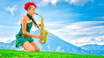 giovane sassofonista donna con i capelli rossi che suona il sassofono nella natura di montagna. foto