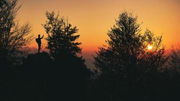 una persona in silhouette fotografa il tramonto foto