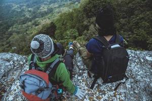 donne e uomini amante asiatici viaggiano nella natura. viaggiare rilassati. sedersi e guardare la vista sulle montagne. su una scogliera sulla montagna. Tailandia