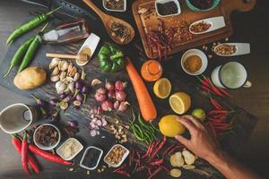 cibo sano erbe spezie da utilizzare come ingredienti da cucina su uno sfondo di legno con verdure fresche biologiche su legno. il concetto di ingredienti alimentari con varietà sul tavolo rustico. foto