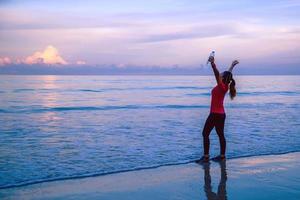 ragazza in esecuzione allenamento jogging sulla spiaggia al mattino. rilassati e felici di correre sul mare. in estate foto