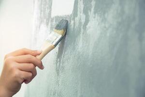 rullo spazzola la pittura, lavoratore pittura su superficie parete pittura appartamento, Restaurare con grigio colore dipingere. partire vuoto copia spazio bianca per Scrivi descrittivo testo accanto. foto