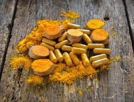 polvere di curcuma e capsule di curcuma su fondo in legno foto