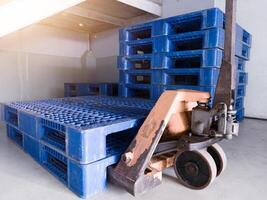 mano pallet Jack e alcuni blu pallet su il distribuzione magazzino la zona. foto