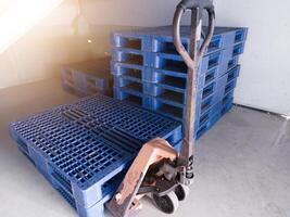 mano pallet Jack e alcuni blu pallet su il distribuzione magazzino la zona. foto