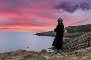 solitario e triste ragazza Guardando tramonto di il mare. brama per il distanza e il passato. foto