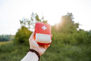 primo aiuto kit su un' escursione contro il sfondo di il raggi di il sole, turista attrezzatura primo aiuto kit per muscolo dolore, un' impostato di medicinali nel un' piccolo Borsa. foto