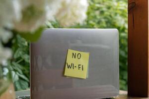 no wi fi testo su carta Nota a il computer portatile su sfondo di verdura giardino di legno alcova all'aperto. concetto di sociale media tecnologia disintossicazione. torsolo natura nucleo sostenibile lento vita foto