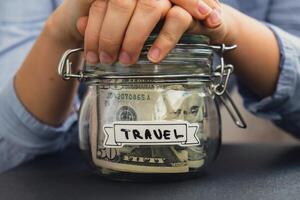 femmina mani Tenere bicchiere vaso pieno di americano moneta dollari denaro contante banconota con testo viaggio. preparazione Salvataggio i soldi. moderare consumo e economia. raccolta i soldi foto