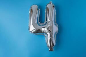 4 quattro metallico Palloncino isolato su blu sfondo. saluto carta argento Foglio Palloncino numero contento compleanno vacanza concetto. copia spazio per testo. celebrazione festa congratulazione decorazione foto