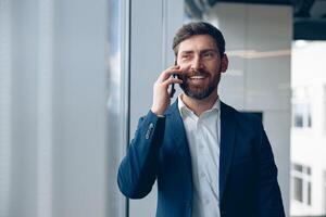sorridente uomo d'affari usi mobile Telefono per chiamata il suo attività commerciale compagno mentre Lavorando nel il ufficio foto