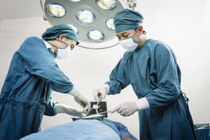 chirurgo che opera il paziente con un assistente in sala operatoria. concetto di chirurgia e emergenza foto