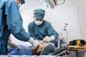 l'assistente chirurgo ha messo il paziente su una maschera di ossigeno-ventilatore in preparazione per l'intervento chirurgico. foto