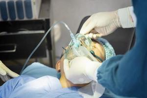 l'assistente chirurgo ha messo il paziente su una maschera di ossigeno-ventilatore in preparazione per l'intervento chirurgico. foto