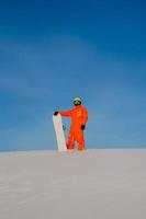 snowboarder freerider con snowboard bianco in piedi in cima alla pista da sci foto