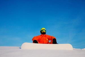 snowboarder freerider con snowboard bianco seduto in cima alla pista da sci foto