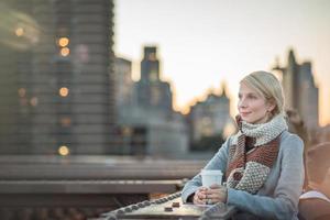 donna sul ponte di brooklyn guardando manhattan con un caffè foto