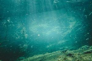 albero morto e raggi di luce in un fiume di acqua limpida foto