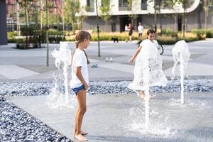 carino giovane sorelle giocando nel fontane. bambini avendo divertimento con acqua su soleggiato estate giorno. attivo tempo libero per bambini. foto