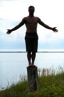 sagoma di uomo che fa yoga su un ceppo in natura foto