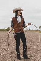 bella Cinese cowgirl lancio il laccio nel un' cavallo paddock foto