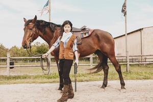 carino Cinese cowgirl mentre assunzione cura di sua cavallo foto