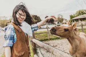 ritratto di un' bellissimo Cinese femmina cowgirl mentre accarezzando un' puledro foto