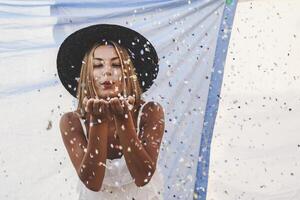 bella donna con colorato cannuccia cappello soffiaggio coriandoli foto