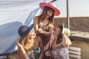 gruppo di femmina amici avendo divertimento mentre mangiare ciliegie su il tetti foto