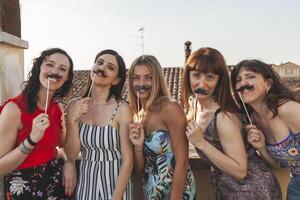 gruppo di femmina amici avendo divertimento con festa Accessori su il tetti foto