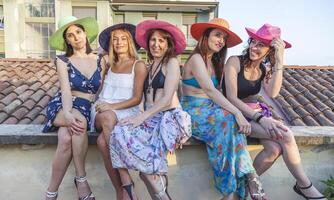 gruppo di femmina amici su vacanza seduta su il tetti foto