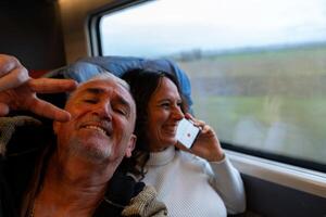 contento mezzo anziano coppia assunzione un' autoscatto seduta su un' treno avendo divertimento Il prossimo per il finestra su vacanza foto