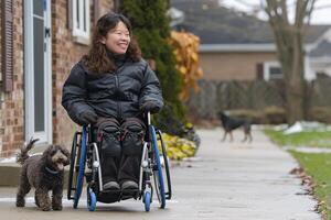ai generato asiatico donna nel sedia a rotelle prendere cane per camminare foto