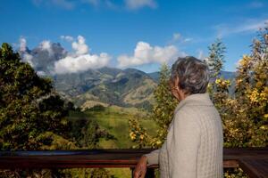 anziano donna turista guardare a il sorprendente paesaggi di il centrale intervalli su il salita per il alto di lettere fra il città di fresno e manizales nel Colombia foto