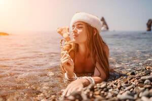 donna viaggio mare. contento turista godere assunzione immagine su il spiaggia per ricordi. donna viaggiatore nel Santa cappello sembra a telecamera su il mare baia, condivisione viaggio avventura viaggio foto