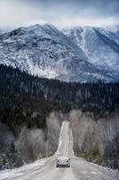 strada diritta invernale con bellissime montagne innevate sullo sfondo foto