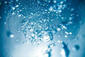 bolle d'aria subacquee astratte che salgono sulla superficie dell'acqua con raggi di luce solare