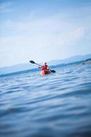donna con giubbotto di sicurezza kayak da solo su un mare calmo