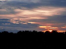 spettacolare tramonto Sopra, arancia sole crescente su al di sopra di il orizzonte foto