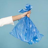 donna che tiene in mano un sacchetto della spazzatura di plastica blu foto