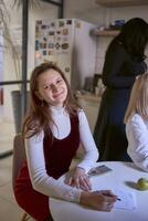 giovane donna sorridente a il tavolo nel il ufficio cucina foto