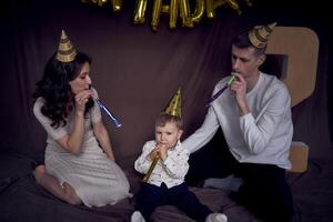 famiglia festeggiare di bambino compleanno indossare festa cappelli soffiaggio tubi foto