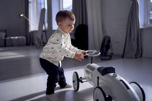 un' bambino piccolo è con entusiasmo giocando con il suo giocattolo auto su il suo compleanno foto