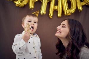 molto emotivo mamma e sua poco compleanno ragazzo mangiare torta foto